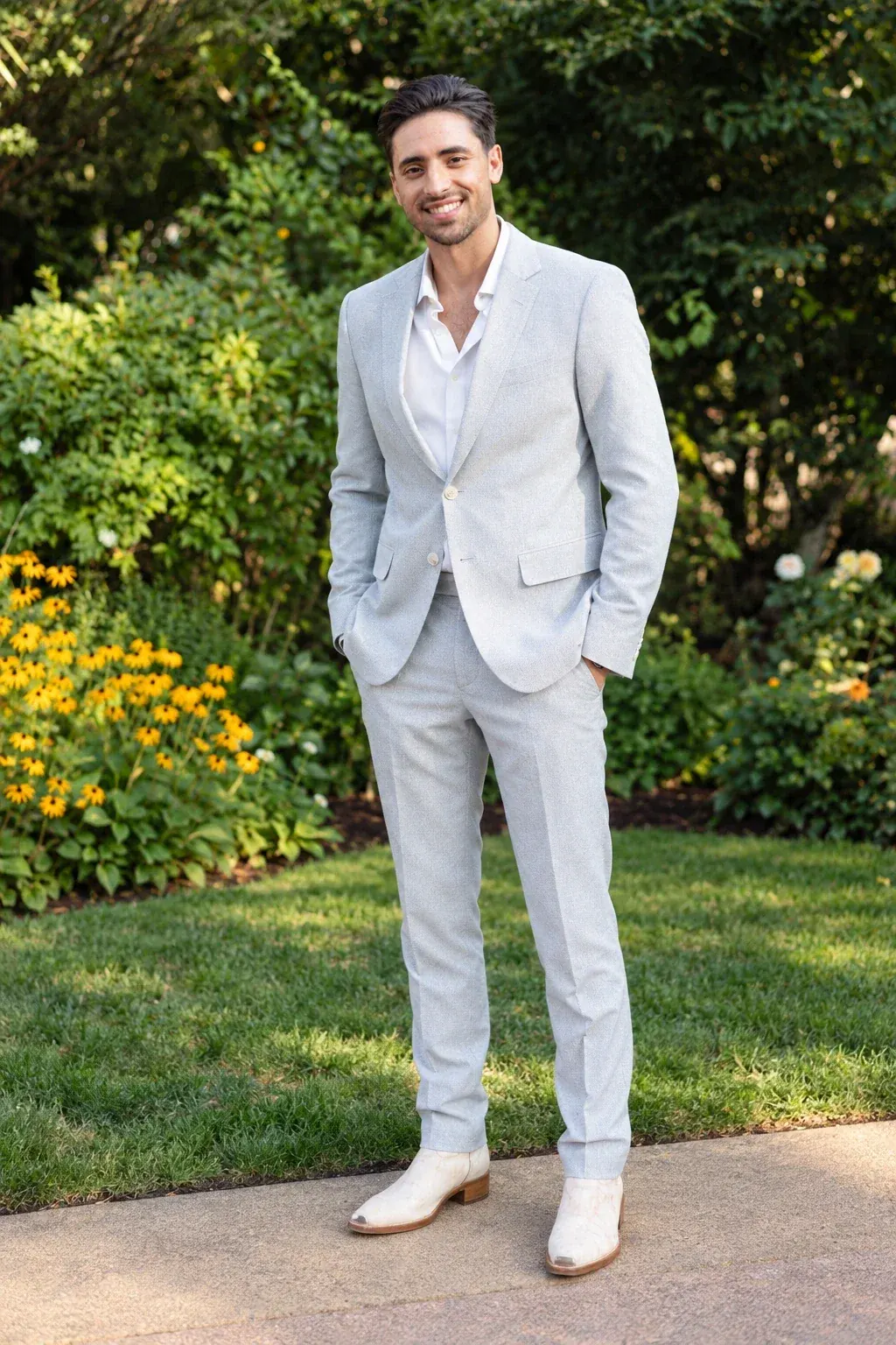 Dr. Payam Zohdi, DDS, smiling in a light gray suit in a garden