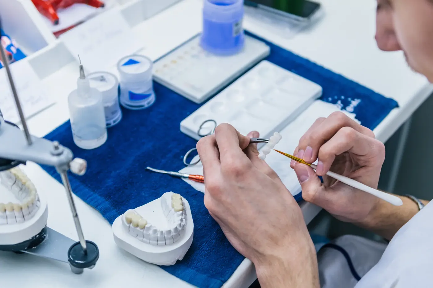 Dental technician shaping and shading a ceramic restoration by hand in a laboratory