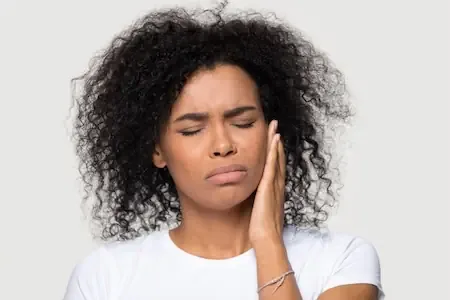 Woman pressing a hand to her jaw in pain from a toothache