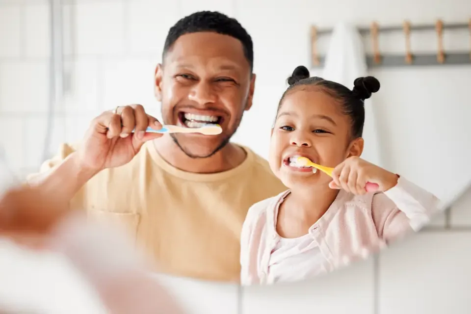 Father and daughter brushing their teeth together in the bathroom